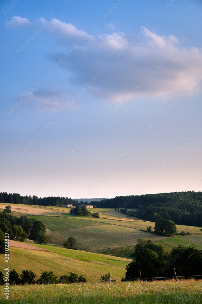 Beautiful evening landscape in the Spessart area in Germany with clouds in the blue sky and agricultural fields