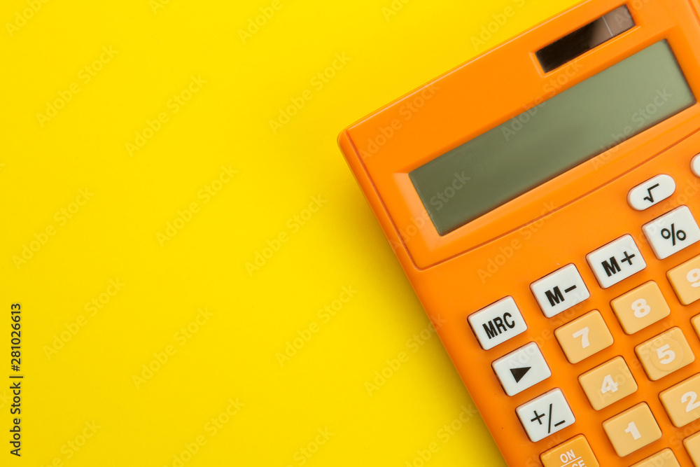 Orange calculator on a bright paper yellow background. Office supplies. Education. back to school. top view. place for text. Orange calculator on a bright paper yellow background. Office supplies. Education. back to school. top view. place for text.