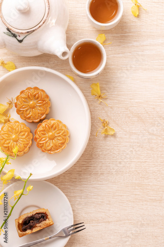 Delicious moon cake for Mid-Autumn festival with beautiful pattern, decorated with yellow flowers and tea. Concept of festive afternoon pastry design