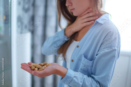 Young sick woman suffers from choking and cough from allergic reaction to peanut. Danger of nuts and food allergy. photo