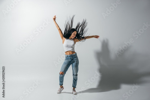 full length view of girl dancing with hands in air on white background
