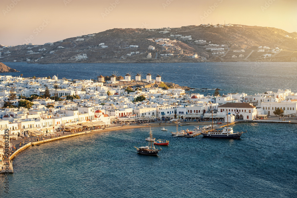 Fototapeta premium Mykonos Stadt mit den Windmühlen und dem alten Hafen bei Sonnenuntergang, Griechenland