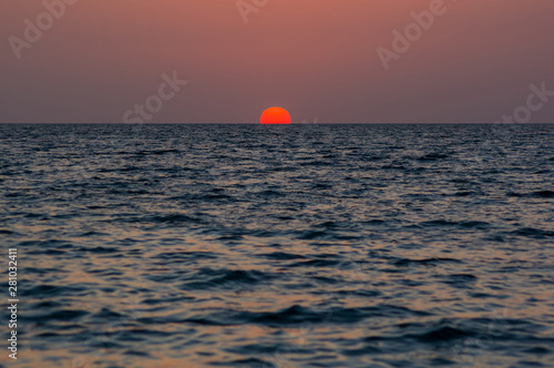 Amazing sea sunset on the pebble beach, the sun, waves, clouds