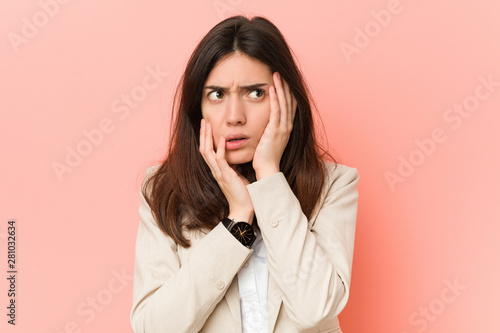 Young brunette business woman against a pink background whining and crying disconsolately.