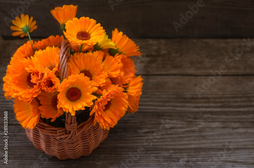Wallpaper Mural Fresh calendula flowers in a wicker basket on on wooden a table Torontodigital.ca