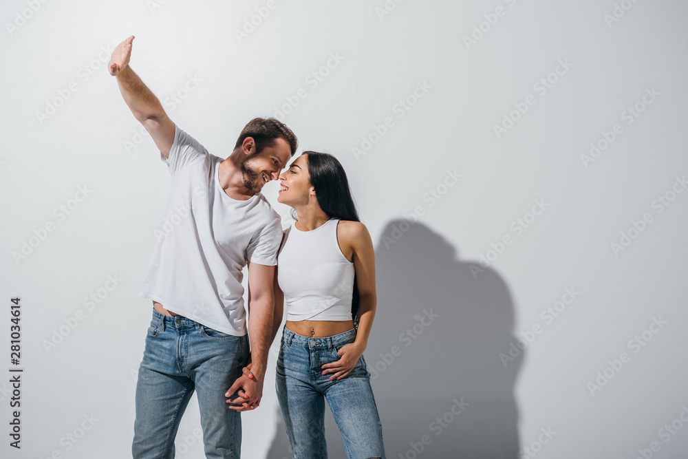 young man covering face from light while smiling and holding hands with girlfriend young man covering face from light while smiling and holding hands with girlfriend