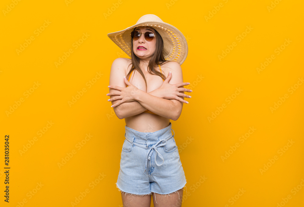 Young caucasian woman wearing a straw hat, summer look going cold due to low temperature or a sickness. Young caucasian woman wearing a straw hat, summer look going cold due to low temperature or a sickness.