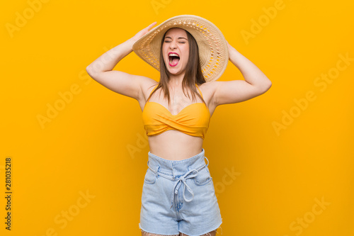 Young caucasian woman wearing a straw hat, summer look covering ears with hands trying not to hear too loud sound.