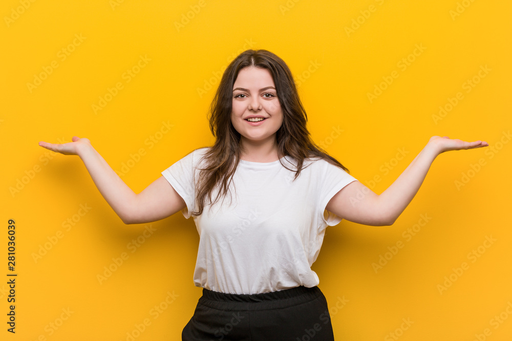 Young curvy plus size woman makes scale with arms, feels happy and confident. Young curvy plus size woman makes scale with arms, feels happy and confident.