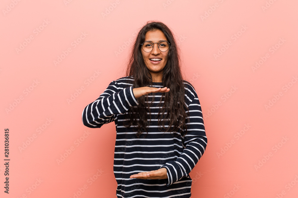 Obraz premium Young intellectual indian woman holding something with both hands, product presentation.
