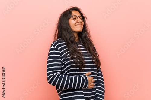 Young intellectual indian woman touches tummy, smiles gently, eating and satisfaction concept.