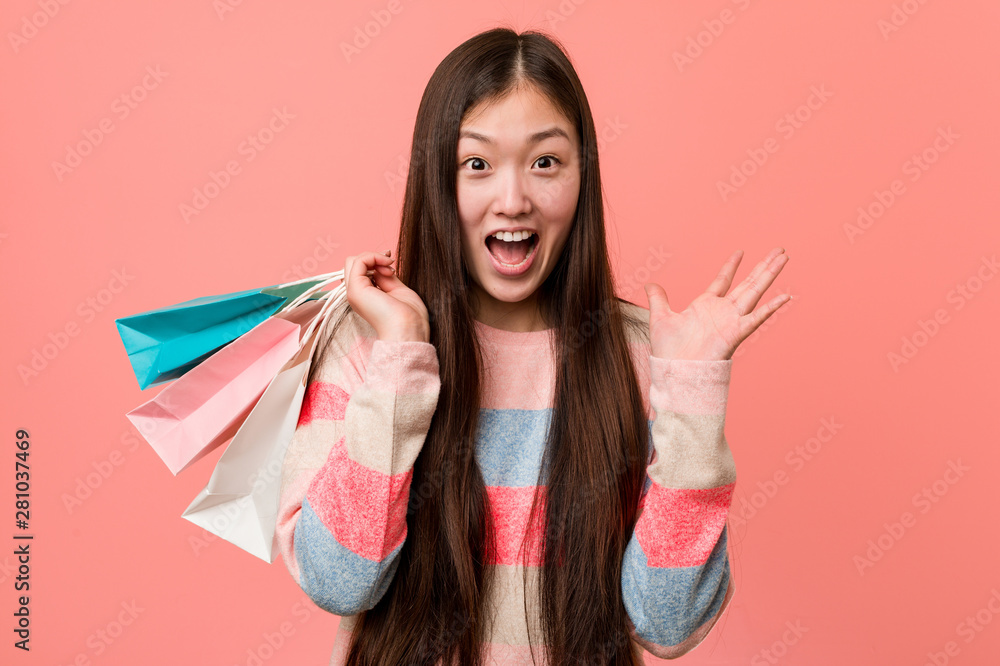 Young asian woman holding a shopping bag celebrating a victory or success Young asian woman holding a shopping bag celebrating a victory or success