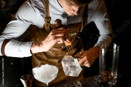 Bartender crushing piece of ice with crusher
