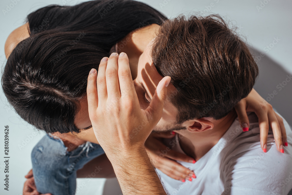Fototapeta premium top view of young couple kissing while man hiding faces with hand