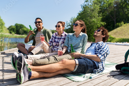 leisure, picnic and people concept - friends drinking beer and cider on lake pier in summer park © Syda Productions