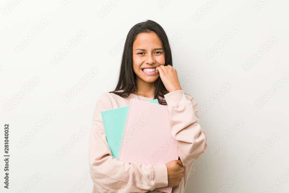 Young hispanic woman holding some notebooks biting fingernails, nervous and very anxious. Young hispanic woman holding some notebooks biting fingernails, nervous and very anxious.