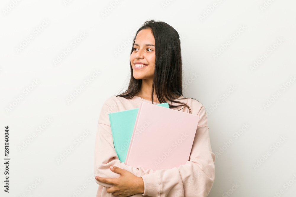 Young hispanic woman holding some notebooks smiling confident with crossed arms. Young hispanic woman holding some notebooks smiling confident with crossed arms.