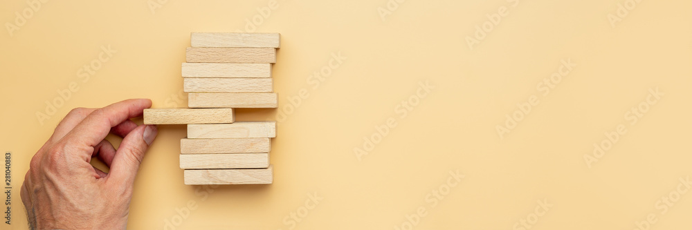 Male hand holding the middle wooden peg in a stack of them