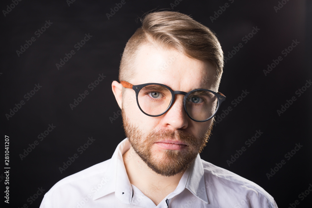 Portrait of young bearded man and in glasses over the black background Portrait of young bearded man and in glasses over the black background