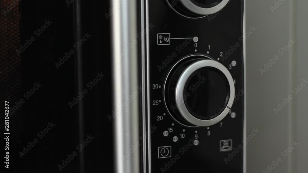 Setting microwave timer to seven minutes and turning microwave off - close angled shot Setting microwave timer to seven minutes and turning microwave off - close angled shot