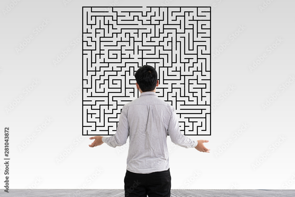 Businessman in doubt looking to a maze and searching the way out Businessman in doubt looking to a maze and searching the way out