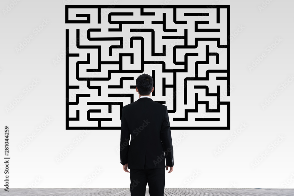 Businessman in doubt looking to a maze and searching the way out Businessman in doubt looking to a maze and searching the way out