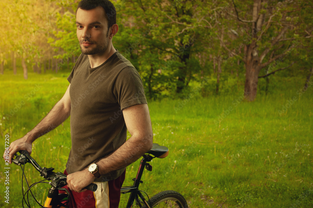 Obraz premium Healthy lifestyle concept. Profile portrait of handsome young man with black hair enjoying sunny summer day in green forest. Beautiful lawn among trees. Text space. Outdoor shot