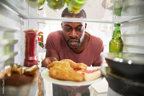 View Looking Out From Inside Of Refrigerator Filled With Unhealthy Takeaway Food As Man Opens Door