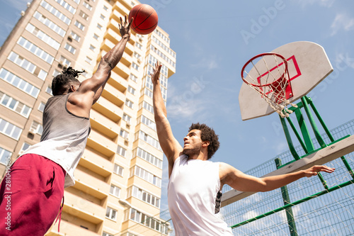 Two young professional intercultural basketball players trying to catch the ball photo