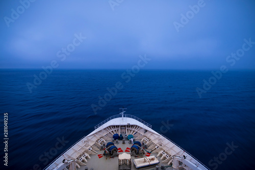 View from the bridge of a ship traveling through fog, long exposure with motion blur on waves.