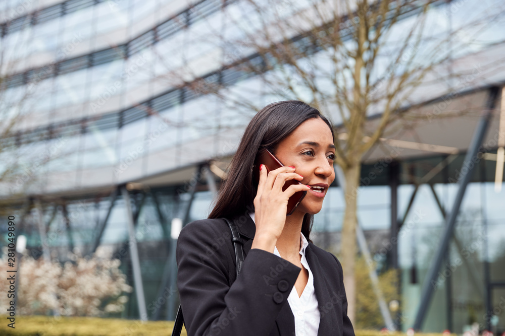 Businesswoman Commuting To Work Talking On Mobile Phone Outside Modern Office Building Businesswoman Commuting To Work Talking On Mobile Phone Outside Modern Office Building