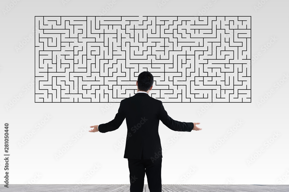 Businessman in doubt looking to a maze and searching the way out Businessman in doubt looking to a maze and searching the way out