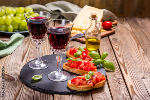Two glasses of red wine and bruschetta, appetizer set on wooden rusitc background