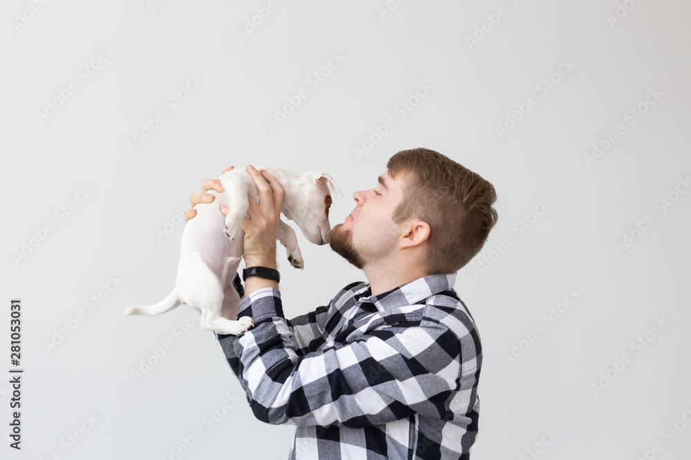 people, pets and animals concept - young man kissing jack russell terrier puppy on white background - obrazy, fototapety, plakaty 