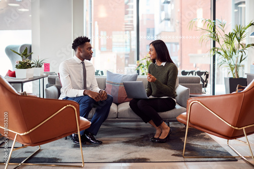Businesswoman Interviewing Male Job Candidate In Seating Area Of Modern Office photo