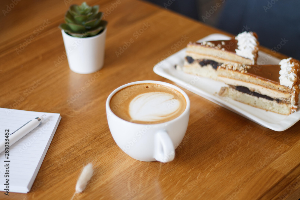 coffee in a Cup with a heart on a wooden table with a notebook and a tablet in a cafe with a flower work in the morning coffee in a Cup with a heart on a wooden table with a notebook and a tablet in a cafe with a flower work in the morning