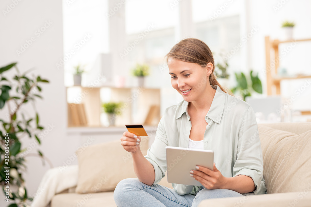 Young casual female shopper with plastic card going to pay for online order Young casual female shopper with plastic card going to pay for online order