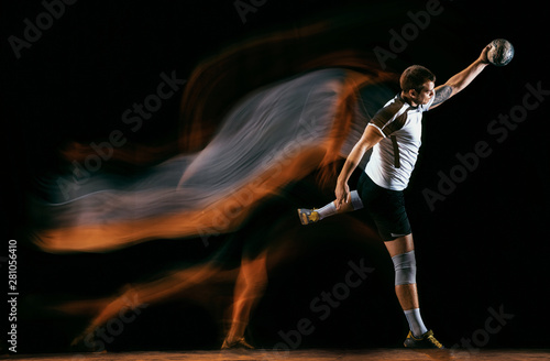 Caucasian young handball player in action and motion in mixed lights over black studio background. Fit male professional sportsman. Concept of sport, movement, energy, dynamic, healthy lifestyle. © master1305