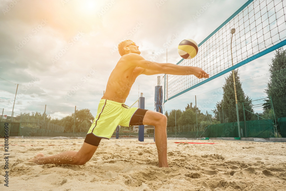 Beach Volleyball player in sunglasses in action with ball under