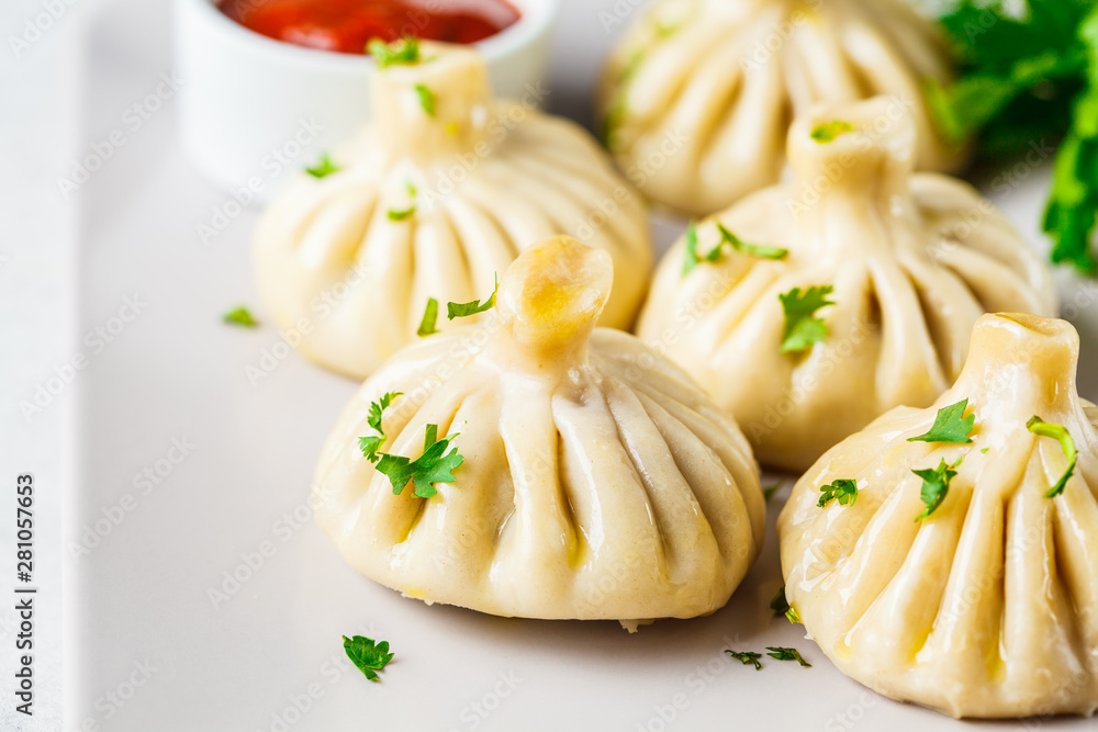 Georgian traditional dumplings khinkali with meat and greens on a white dish. Georgian traditional dumplings khinkali with meat and greens on a white dish.