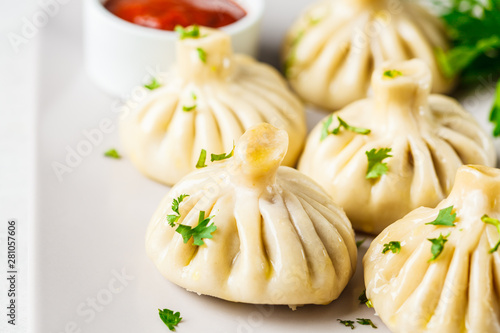 Georgian traditional dumplings khinkali with meat and greens on a white dish.