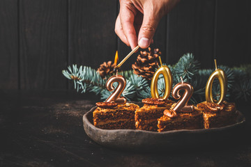 New year 2020. Festive cake with candles on dark background, copy space.