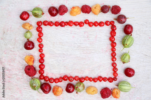 Rectangular frame made up of natural fresh organic berries of red currant on a white wooden background. Top view