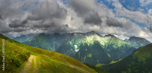 Canvas Print View of narrow path in summer mountains beneath thundery clouds