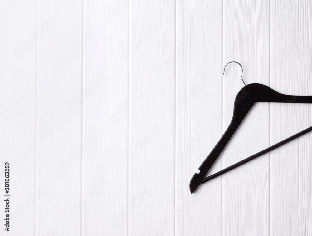 Top view flat lay single black wooden hanger at wooden background.