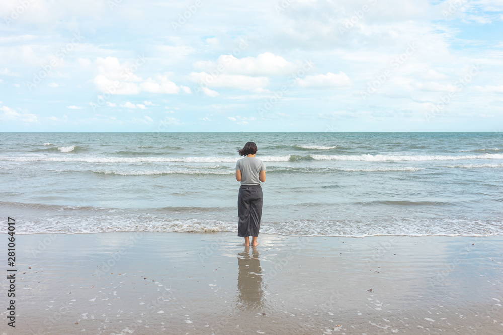 Asian young woman standing facing the sea. Feeling really lonely, heartbroken sea like a nursery of clearing the mind. The concept of liberation travel alone. Asian young woman standing facing the sea. Feeling really lonely, heartbroken sea like a nursery of clearing the mind. The concept of liberation travel alone.