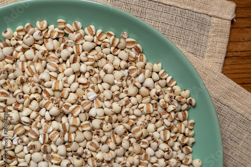 Picture of millet or job’s tears in a green dish that is grains and food on a brown tablecloth, wood grain, suitable for food advertising,top viwe photo