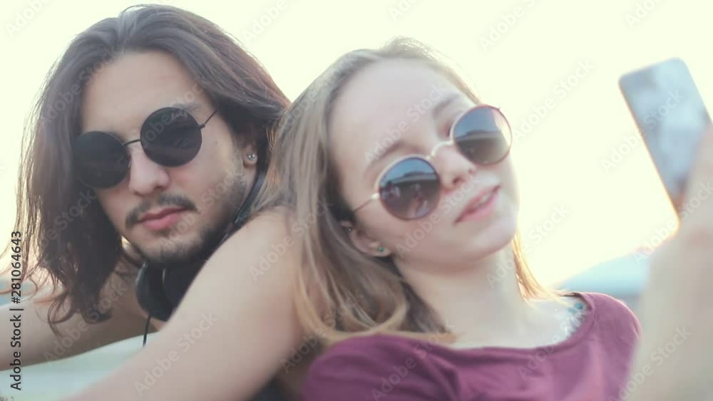 Young couple in round glasses taking a selfie outdoors Young couple in round glasses taking a selfie outdoors
