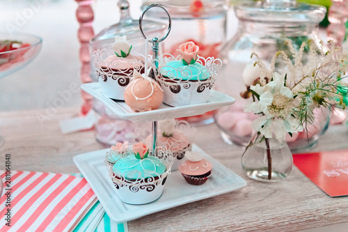 Close-up of multi colored cupcakes on many tier pedestals ready for a picnic, buffet or an away wedding ceremony, selective focus photo