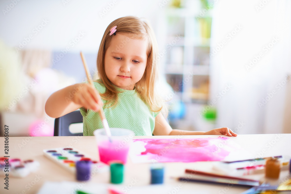 joyful girl child draws gouache in different colors on a white sheet of paper. joyful girl child draws gouache in different colors on a white sheet of paper.